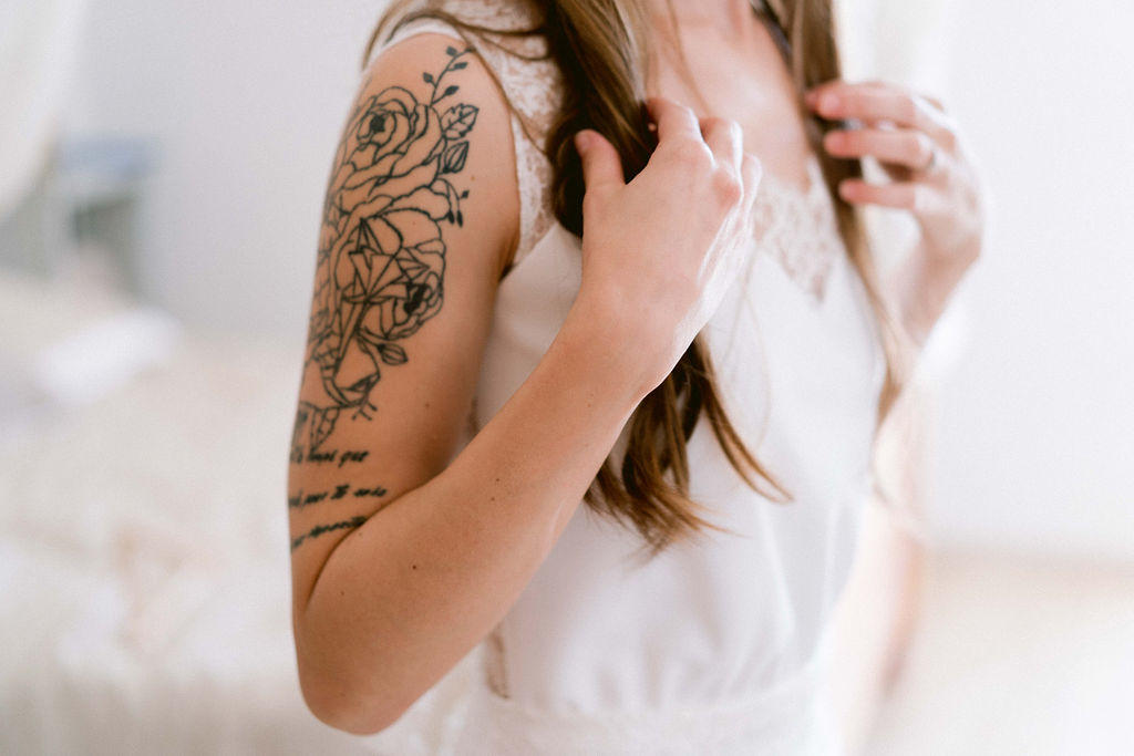 Les tatouages fleurie de la mariée sont parfait avec sa robe longue et simple.