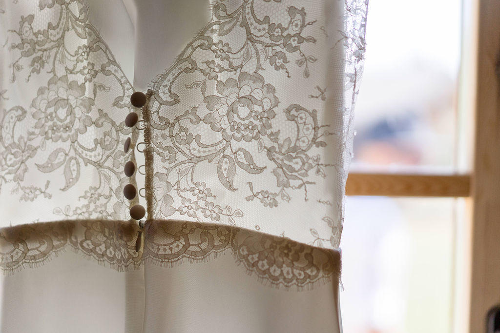 Une robe de mariée avec une joli dentelle de calais fermée par des boutons recouvert.