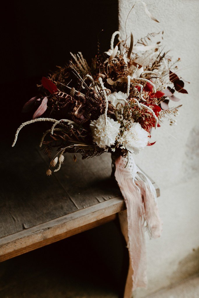 Ce bouquet composé de cymbidium, amarante, oeillet et was flower ainsi que pour le feuillage des fougères et de l'eucalyptus