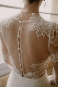 Le dos de la robe de mariée est fermé par des boutons.