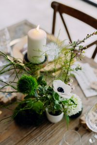 Ambiance intime d'un mariage d'hiver en intérieur, avec une décoration de table romantique illuminée par des bougies et des touches de verdure.
